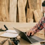 Technology Tools - Man Using a Laptop at a Wood Workshop