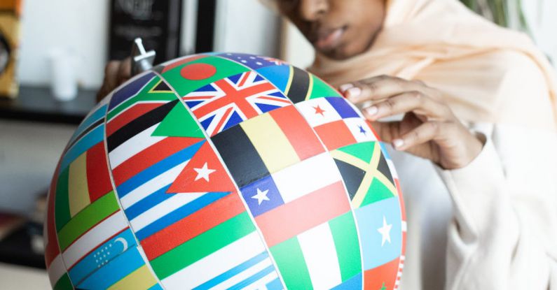 International Study - Concentrated African American female in traditional Muslim clothes and eyeglasses finding flag of country on globe
